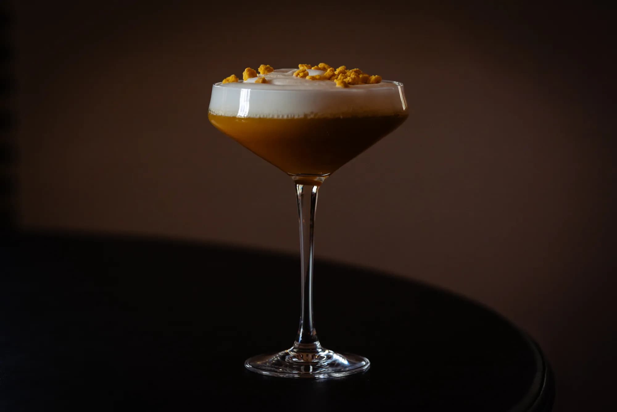 Cocktail met schuimkraag en garnering in een coupeglas